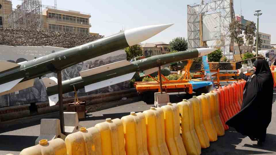 An Iranian woman looks at several Taer 2 missiles on display