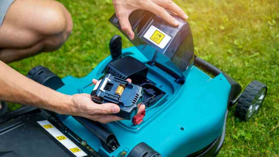 Lawnmowers at Stiftung Warentest: Man holds the battery from the lawnmower in his hand