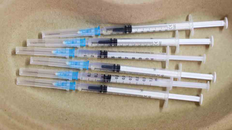 Delta Coronavirus Vaccination: Syringes with vaccine lie in a jar