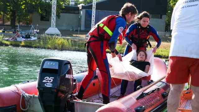 Sports in Munich: A girl mimicking an injury is lifted ashore with a sling.