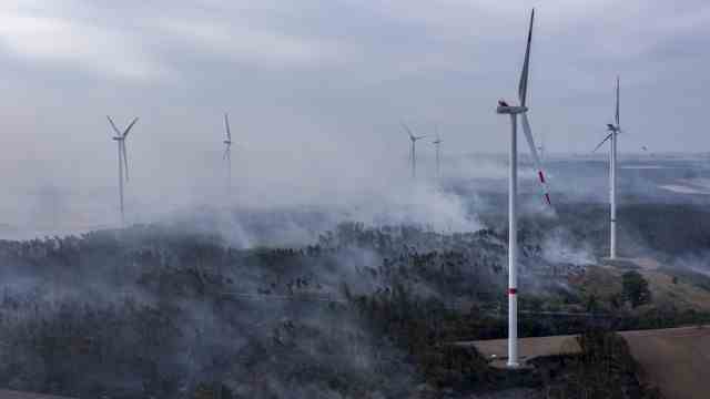 Forest fires: Plumes of smoke from the fire rise between the wind turbines.