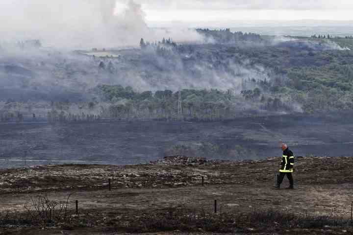 A firefighter in front of a view of the Monts d'Arrée (Finistère) during a fire, July 22, 2022. (MAXPPP)