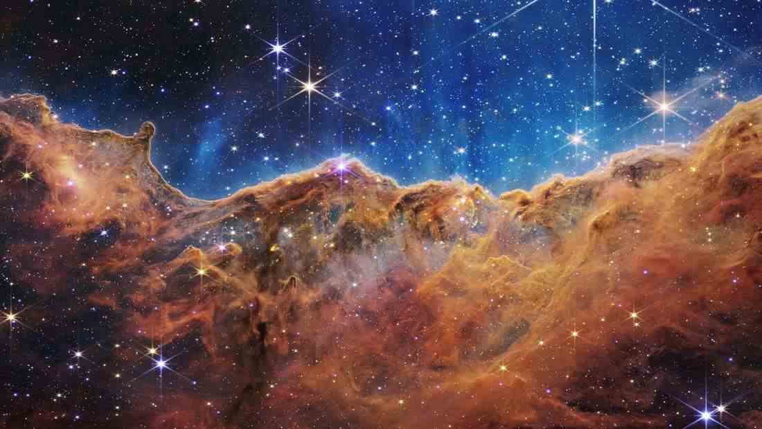 The star-forming region of the Carina Nebula as seen by the James Webb Space Telescope.  The higher contrast, the richness of detail and the galaxies that can be seen everywhere in the background are very striking.