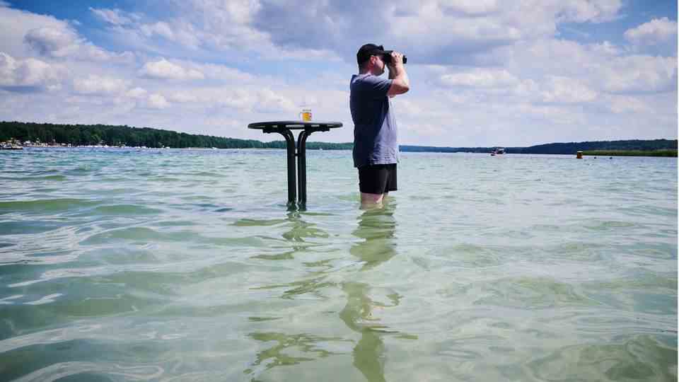 Heat wave Germany: A man cools off with beer in the water