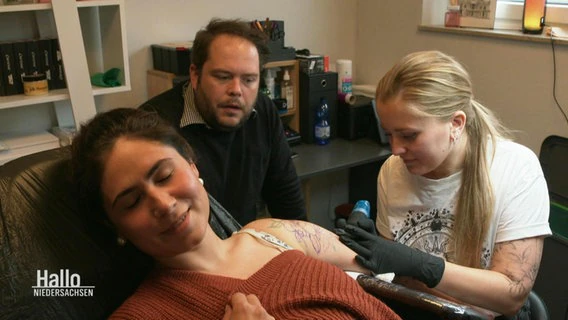 Reporter Jan Bockemüller looks on as a tattoo artist creates a new motif for a customer.  ©screenshot 