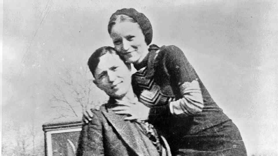 Bonnie and Clyde in front of a car