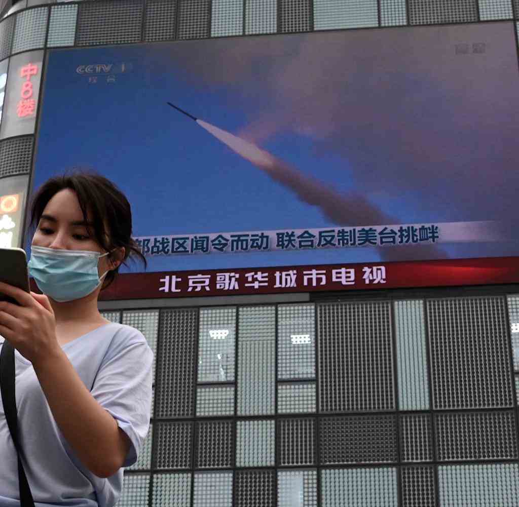 A woman stands in front of a public screen of state television CCTV in Beijing