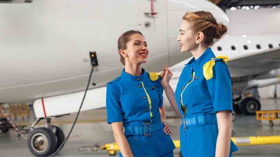 Two flight attendants stand in front of an airplane before the flight