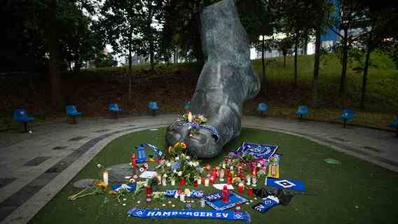 Candles, flowers and scarves stand and lie on and in front of a bronze in front of the Volksparkstadion, which is supposed to represent the foot of the former soccer player Uwe Seeler.  © picture alliance/dpa |  Daniel Reinhardt Photo: Daniel Reinhardt