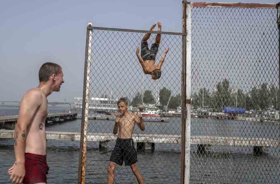 Mykolaiv, Ukraine.  Hopefully they can forget the war for a while while playing: children and young people in the embattled port city show their acrobatic skills while bathing in the river.