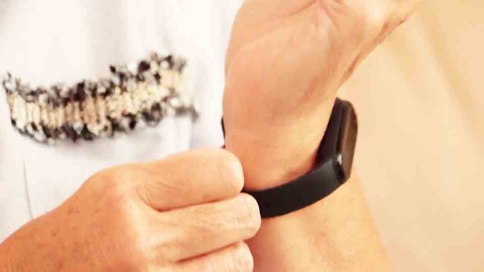 Person puts fitness tracker on wrist