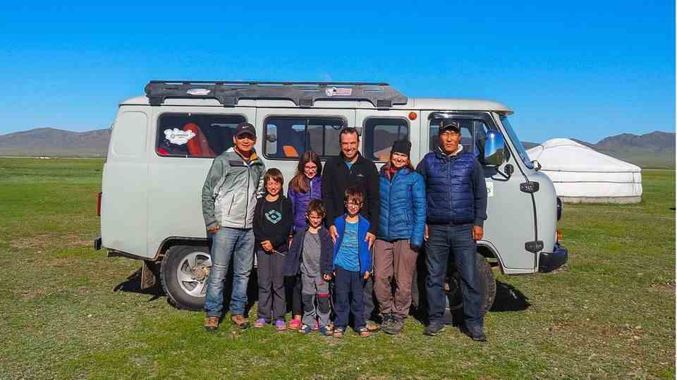 The whole family together with two guides in front of their vehicle, which takes them across Mongolia