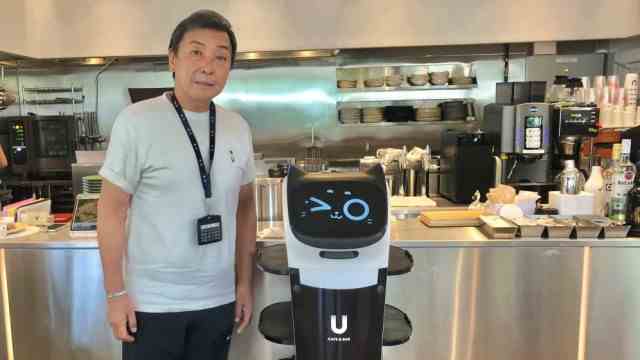 Holiday in Japan: Chikao Watabe, manager of a dining café, with a service robot.  In Japan, people remain very careful to stay away from the virus.