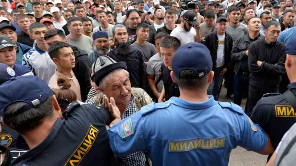 Police officers push back Kyrgyz volunteers who are gathering in front of the government building and are declaring their deployment to the conf