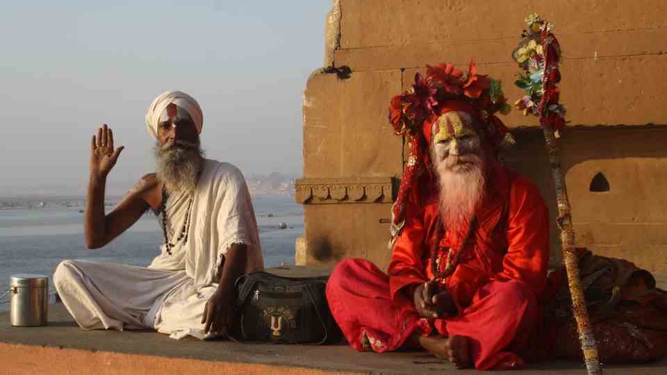 Two Indian men in traditional dress sit on the ground