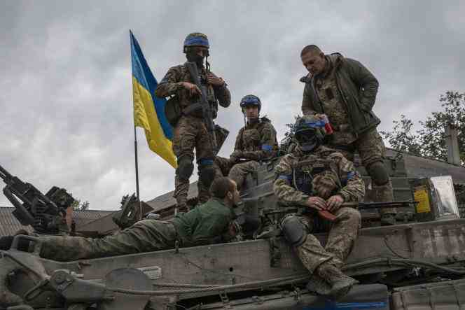 A captured Russian soldier lies on a tank surrounded by Ukrainian soldiers, in Izium, Ukraine, September 11, 2022.