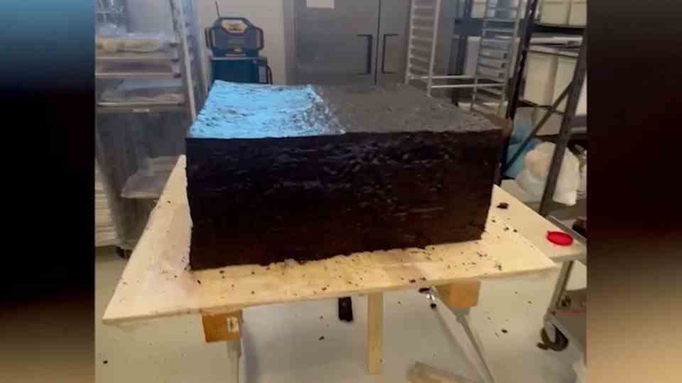 A giant brownie sits on a table in a bakery.