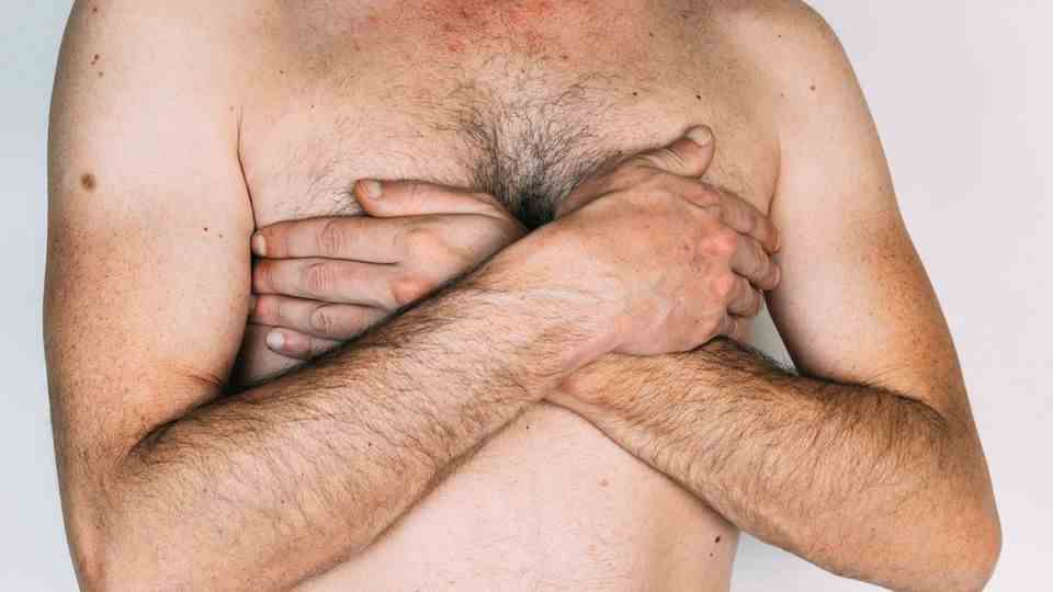 A man covers his breasts with his hands