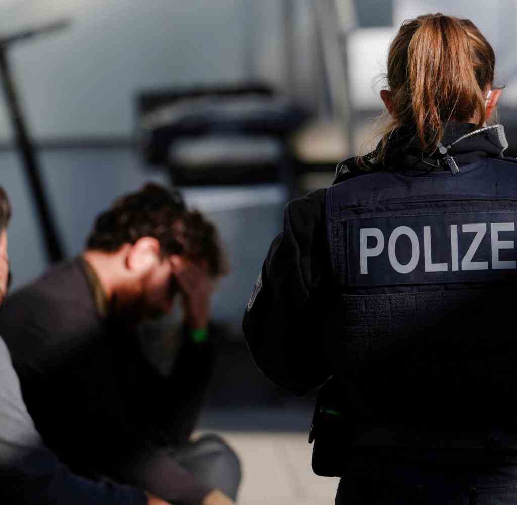 Deutsche Polizeibeamte halten zwei Migranten, die aus dem Irak kommen sollen, während einer Patrouille im Oktober 2021 nahe der deutsch-polnischen Grenze in Frankfurt (Oder) fest