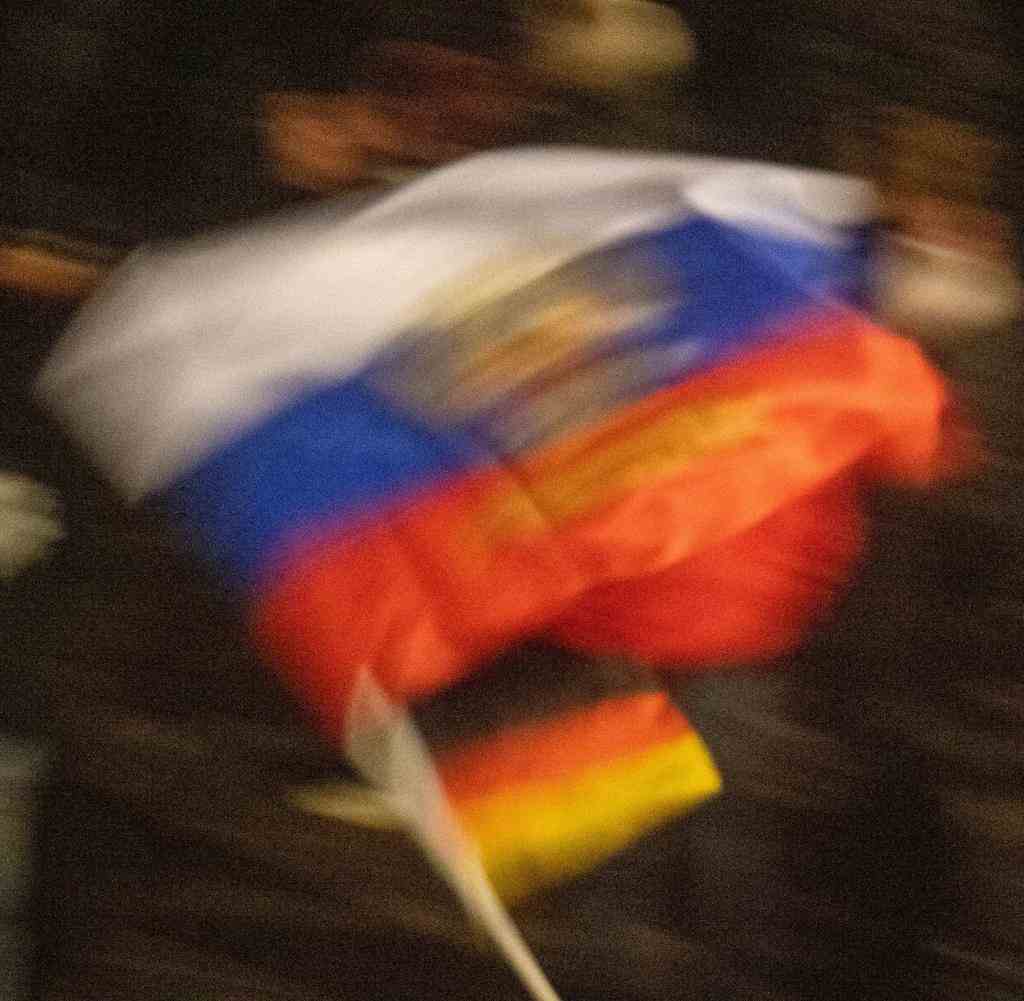 Eine Demonstrantin schwenkt eine russische und eine deutsche Flagge.