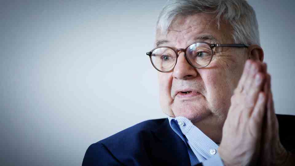 Joschka Fischer with folded hands and looks to the right