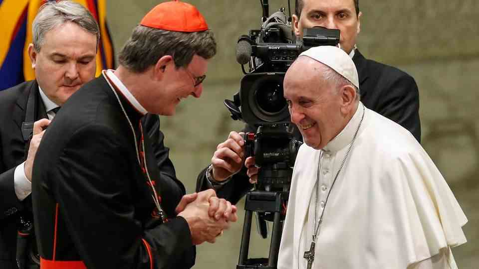 Cardinal Woelki stands next to Pope Francis.  Behind is a cameraman.