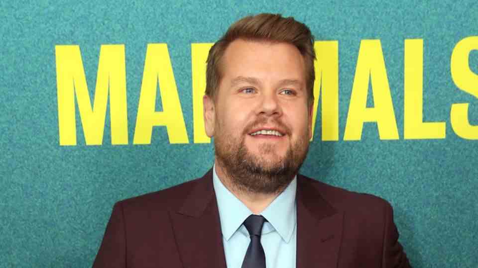 James Corden stands in front of a wall