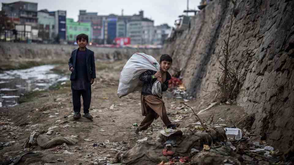 Two boys search for plastic bottles on the banks of the Kabul River