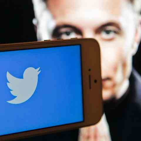 Mobile phone with Twitter icon, Elon Musk on background