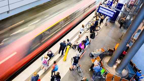 Travelers are standing at a platform where a train is arriving.  Photo: Christoph Soeder