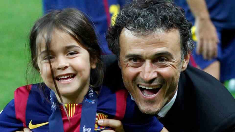 Luis Enrique and his daughter Xana sitting on a trophy