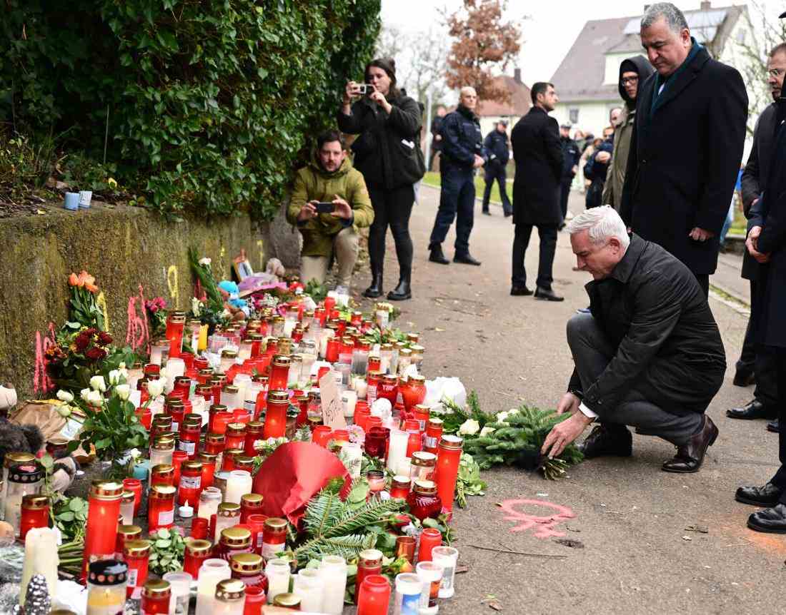 Thomas Strobl (3.v.r., CDU), Innenminister von Baden-Württemberg, und Ahmet Basar Sen (4.v.r.) , Botschafter der Türkei in Deutschland, stehen am Tatort eines Messerangriffs auf zwei Mädchen bei einer Schweigeminute vor niedergelegten Blumen und Kerzen