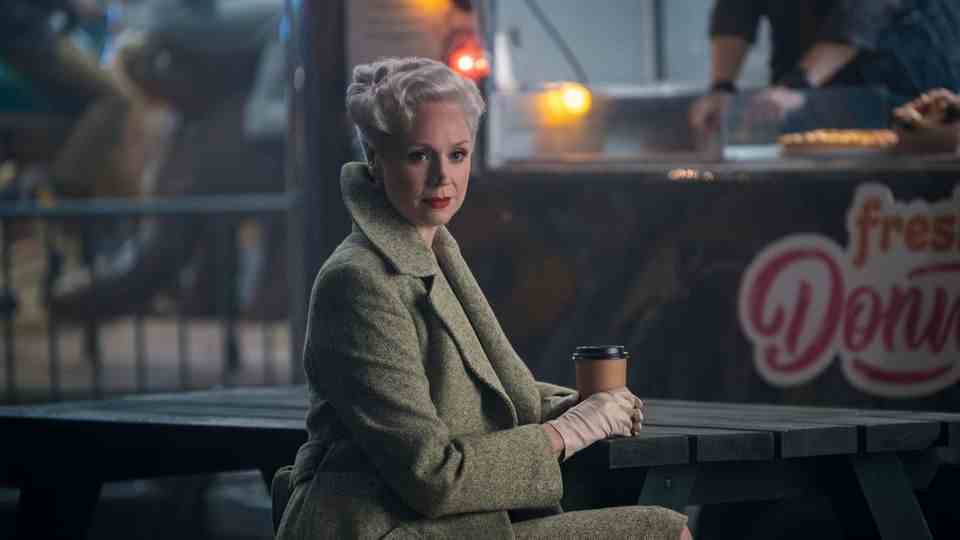 Gwendoline Christie, in her role as Larissa Weems, sits at a picnic table with a cup of coffee
