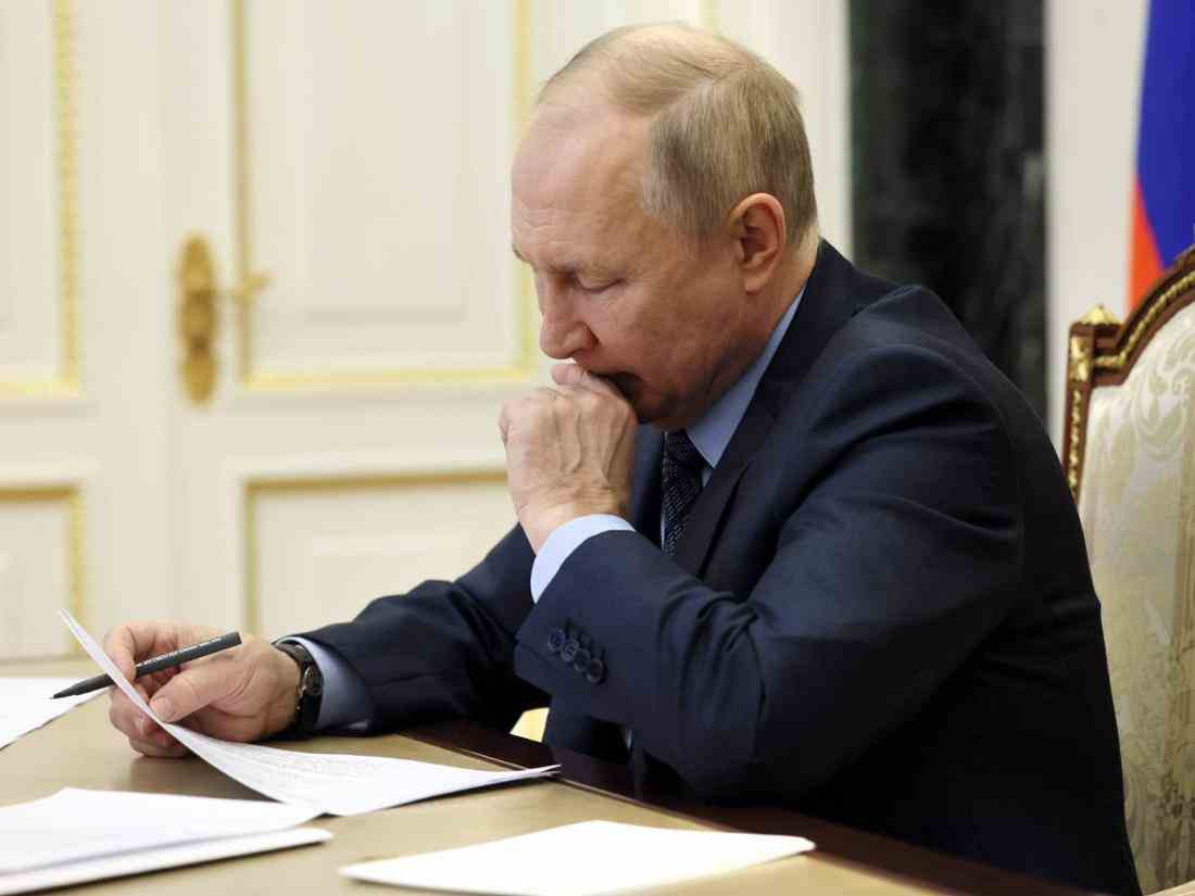 Wladimir Putin sitzt an einem Tisch und liest ein Blatt Papier