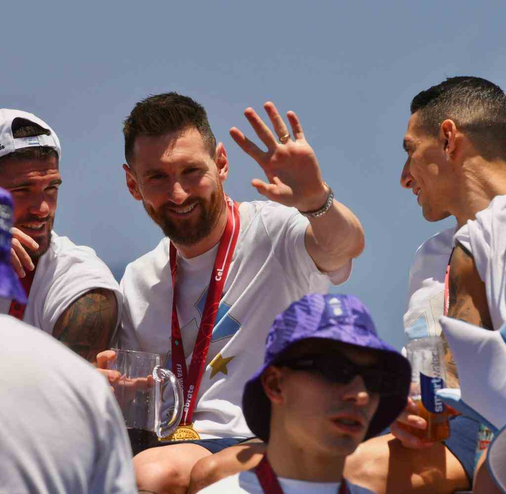 Lionel Messi (centre) waves as he drives into town with the Argentine soccer team