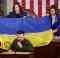 Volodymyr Zelensky speaks in front of a handed-over Ukrainian flag signed by front-line soldiers in Bakhmut