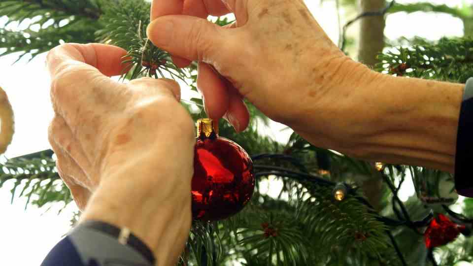 A person hangs a Christmas ball on a Christmas tree
