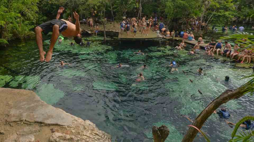 People bathe in Cenote Azul in. Mexico