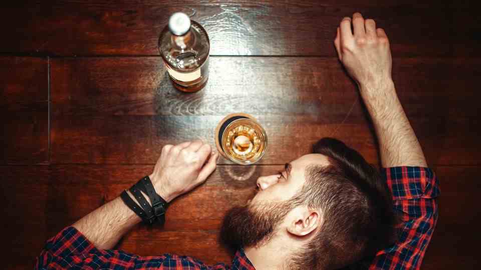 A man rested his head on the table next to a whiskey glass