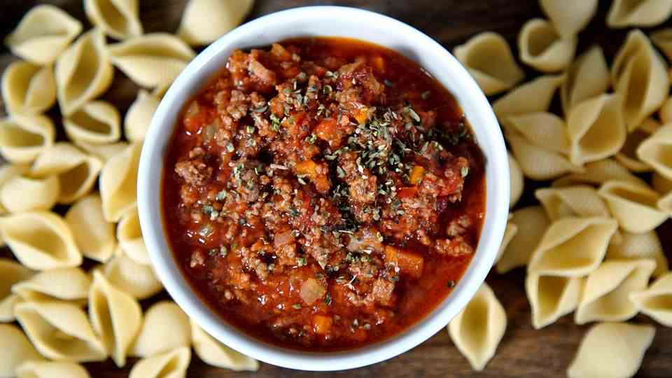 A bowl of Bolognese.  There are noodles all around.