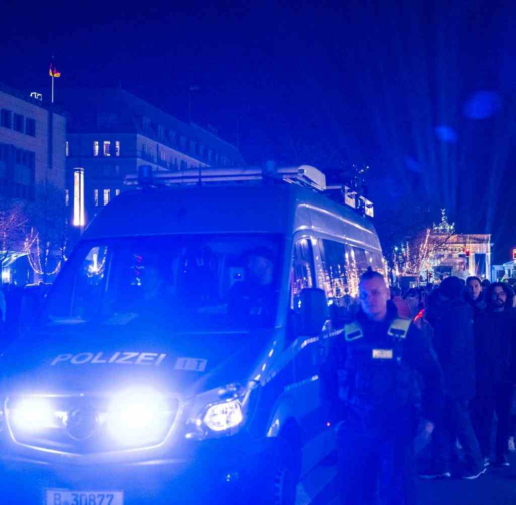 A police car makes its way through the crowd at the Brandenburg Gate