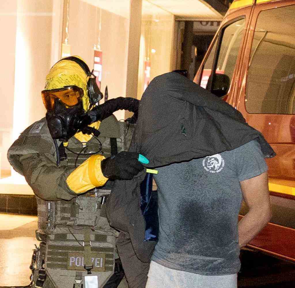 A man is taken into custody by an officer from the special task force (SEK) wearing a protective mask