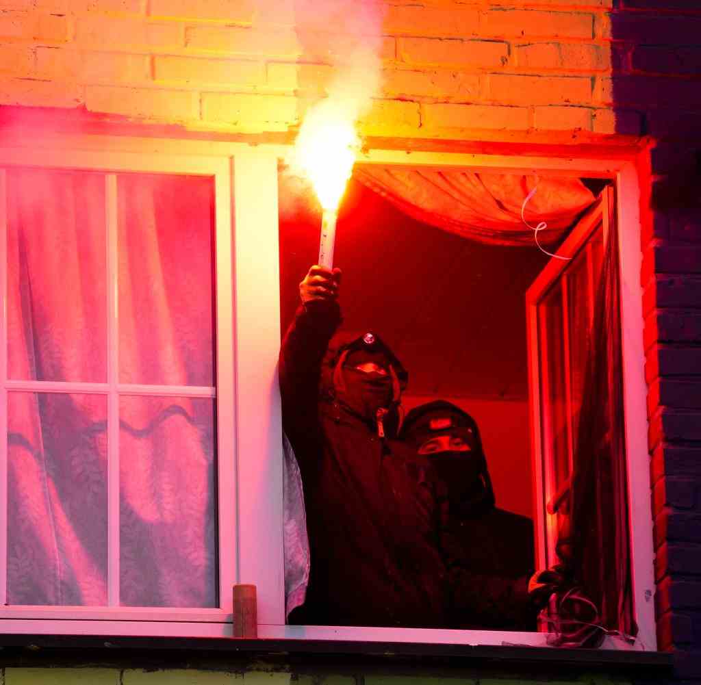 Activists in Lützerath stand at the window of a house with torches