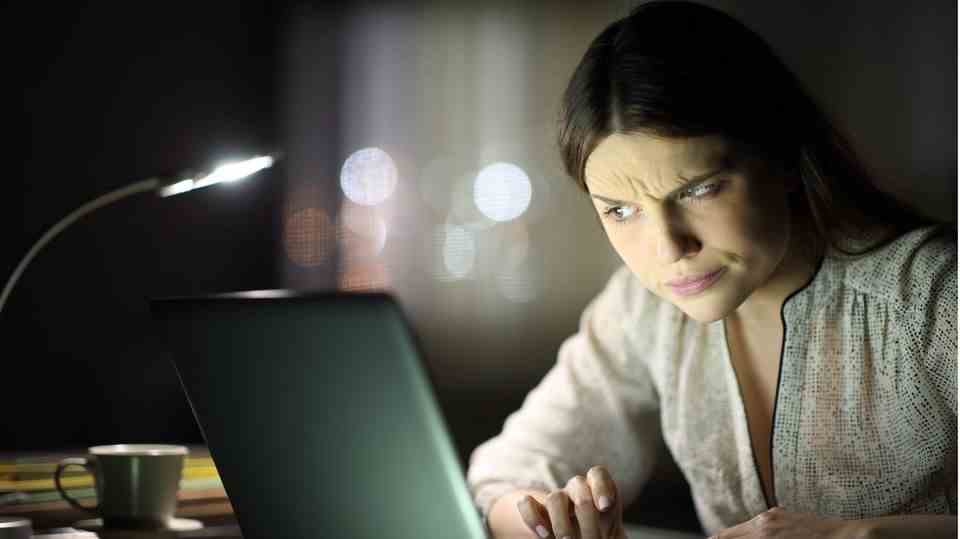 A young woman looks skeptically at her computer