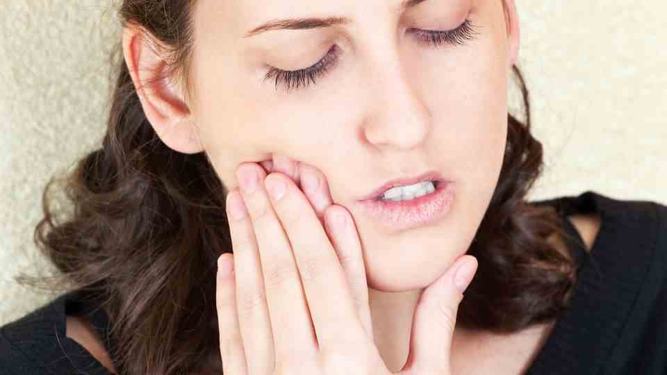 Toothache: A woman is holding her cheek