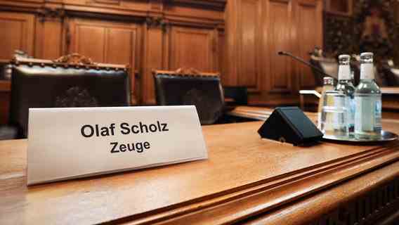 A sign with the text "Olaf Scholz witness" stands in a seat on the Senate pew before the start of a session of the Parliamentary Inquiry Committee "Cum Ex" in the plenary hall of the Hamburg Parliament in the town hall.  © picture alliance / dpa Photo: Christian Charisius