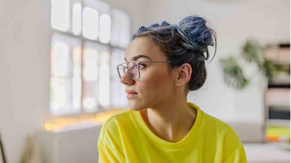 Woman with glasses and yellow sweater looks to the side