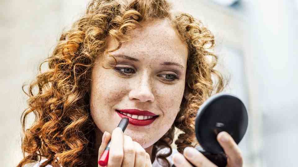 Woman applies red lipstick