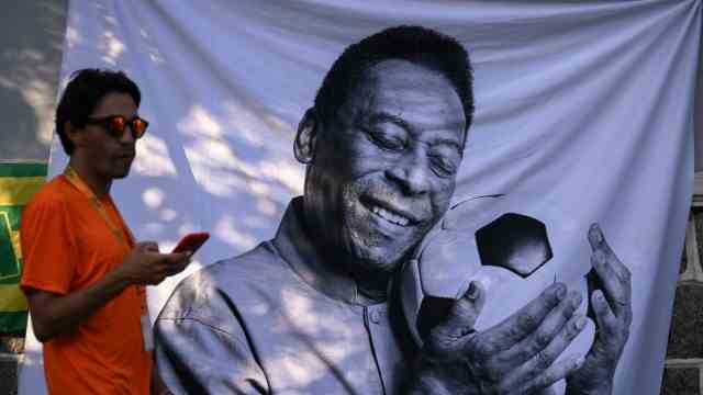 Vigil in Brazil: his friend, the ball: a passer-by in Santos in front of a portrait of Pelé.