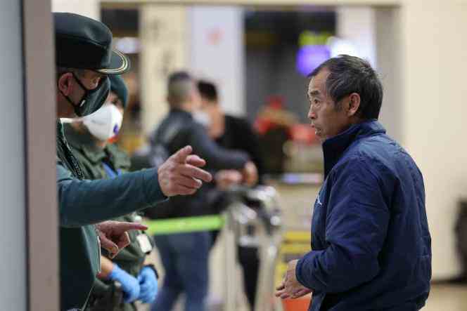 A passenger on a flight arriving from Beijing listens to instructions from a Spanish civil guard, Saturday, December 31, 2022, at Madrid airport. 